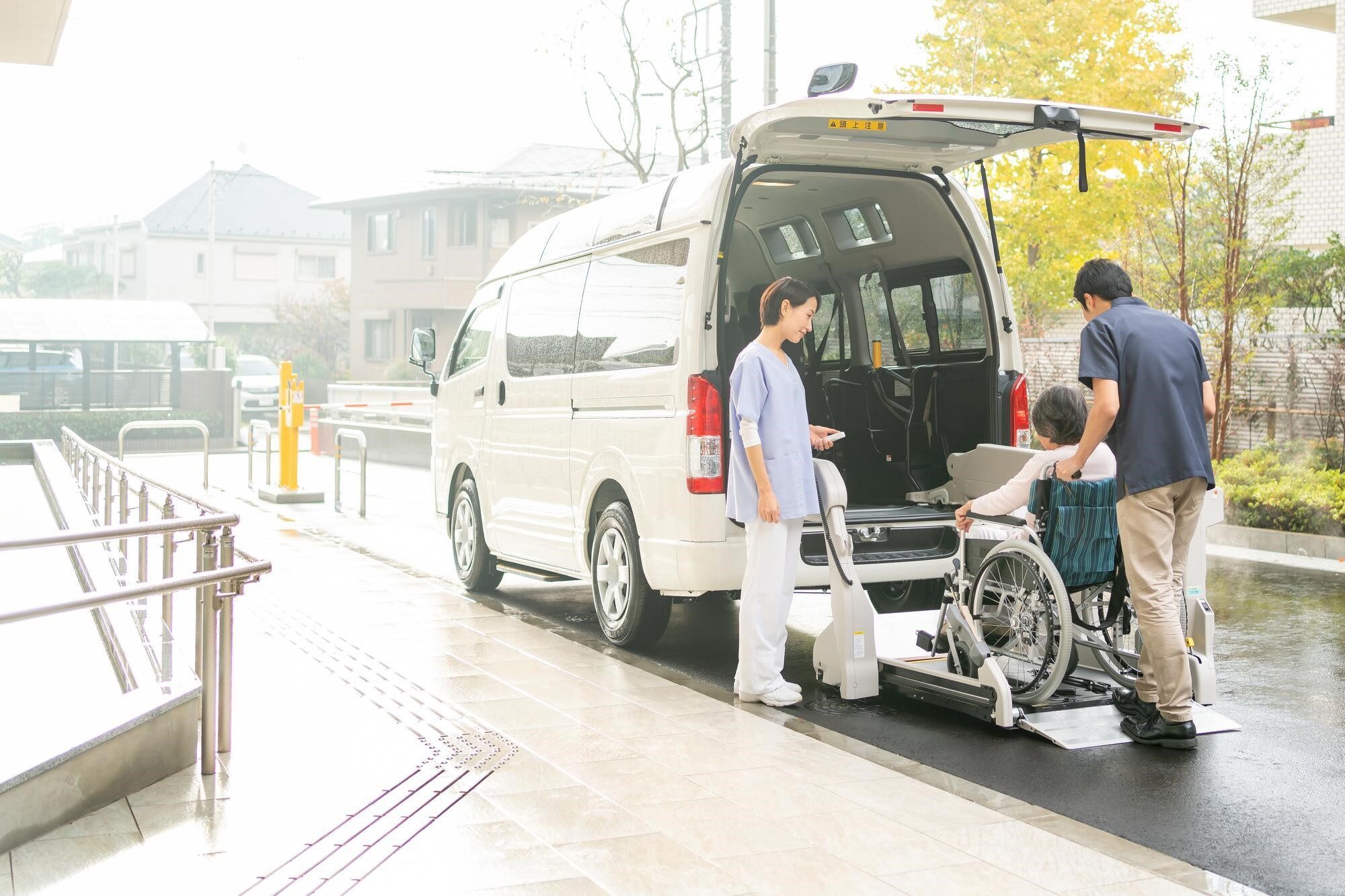 介護施設の送迎車両に乗り込む要介護者と介護スタッフ